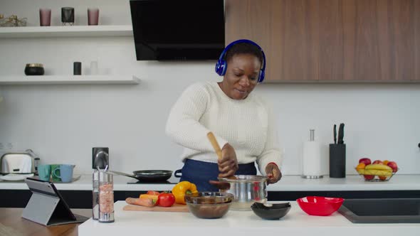 Carefree African Woman Enjoying Music During Cooking