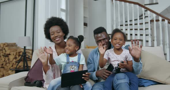 African American Family with Kids which Sitting on the Couch in front of Camera and Waving hands