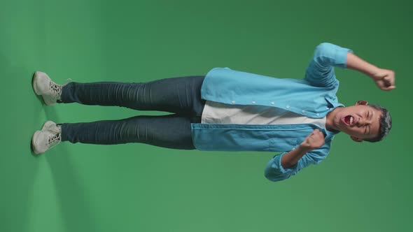 Full Body Of Cheerful Young Asian Boy Celebrating While Standing On Green Screen In The Studio