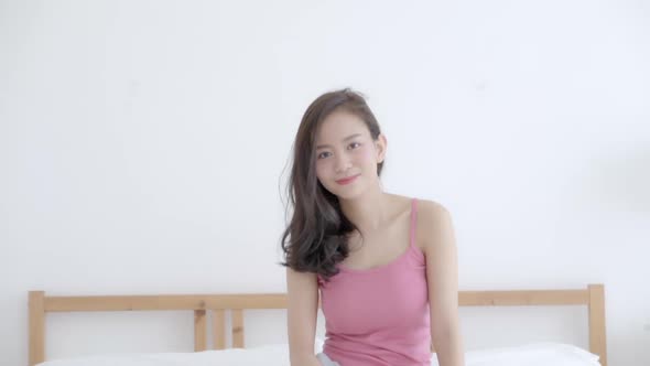 Beautiful portrait young asian woman with smiling and laughing sitting on bed in bedroom.
