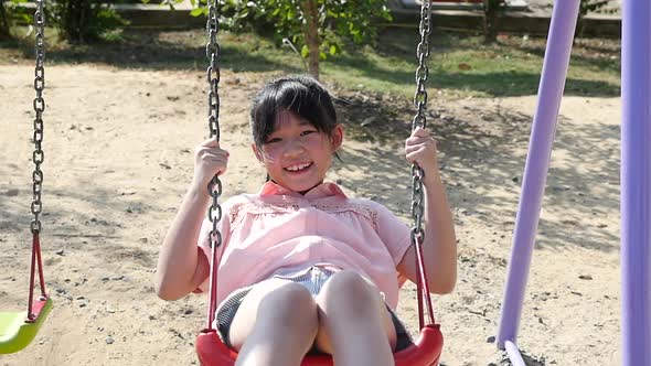 Cute Asian Girl Playing Swing In The Park