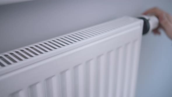 A Man Warms His Hands with His Fingers on the Radiator