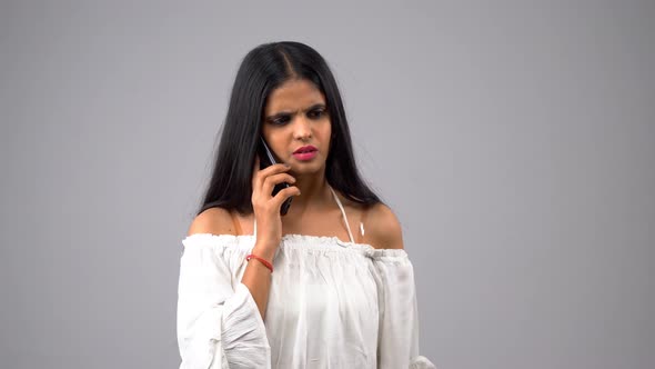 Confused Indian girl talking to someone using smartphone