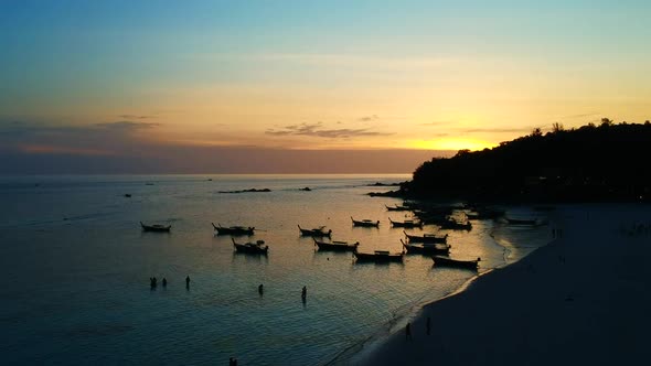 Silhouette shot of a beach line with shadow of people walking on the seaside, boat being dock and mo