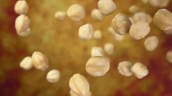 Close-up of Peeled Hazelnuts Falling Down on a Yellow Ochre Background