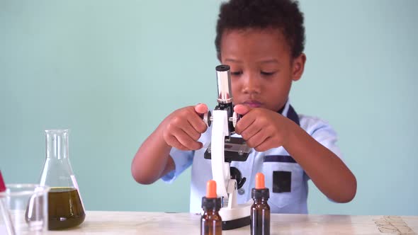 Young African American Kid Using Microscope in Lab