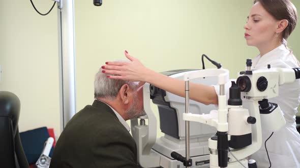 Doctor Examines Elderly Man's Eye on Screen of Autorefractometer