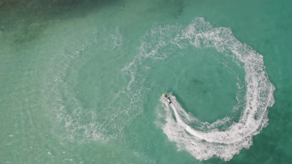 Aerial top view of jet ski or boat drawing a shape on sea ocean turquoise water. Adventure