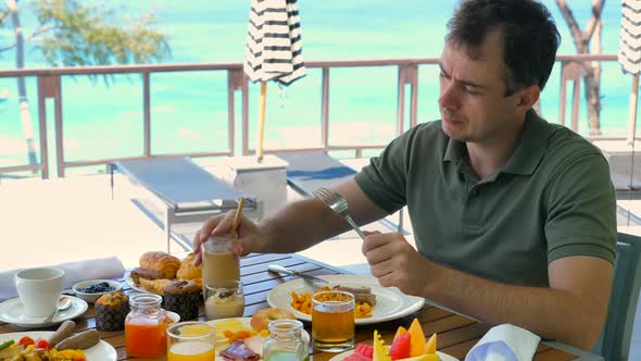 Young Man Have Breakfast or Brunch at Luxury Restaurant in Hotel with Turquoise Sea Background