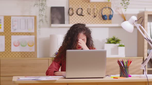 Asian woman sitting at desk in front of laptop stressed out face and headache shows her stressful