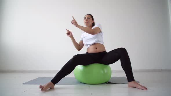 Young Pregnant Woman Goes in for Sports in a Living Room