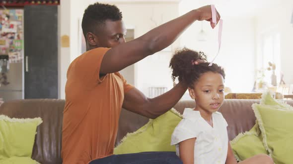 African american father tying his daughter hair