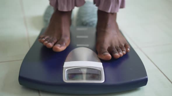 Closeup Bathroom Scales with Barefoot African American Female Feet Stepping on Device