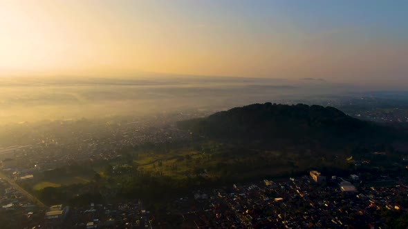 Mount Tidar on picturesque sunrise and Magelang city covered in fog, aerial view