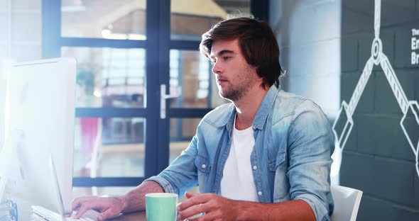 Man having coffee while working on computer