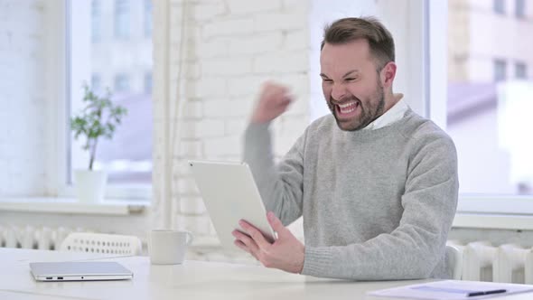 Creative Man Celebrating Online Success on Tablet