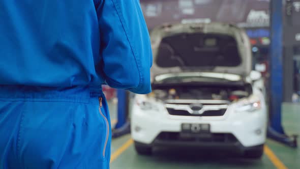 Asian automotive mechanic repairman look under car condition in garage.