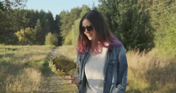 Young Beautiful Girl with Ripe Sunflower in Hands