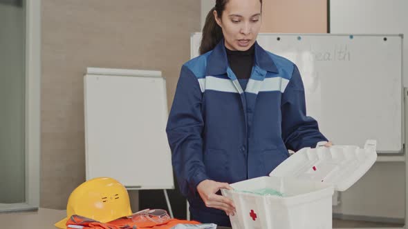 Woman Showing Contents Of First Aid Kit At Industrial Facility