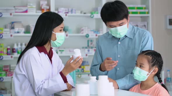 Asian Pharmacist in medical mask explaining the medication to patient in drug store