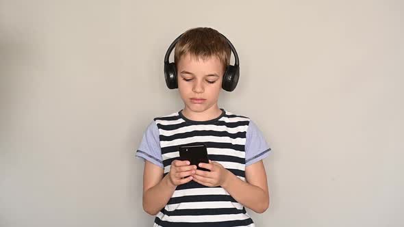 Teenage Boy Texting Using Smartphone Listening To Music Wearing Headphones