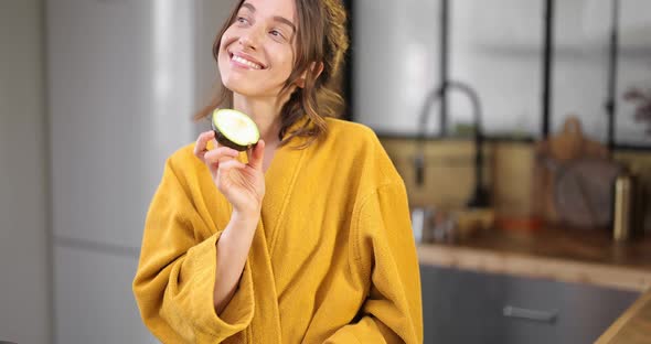 Happy Woman with Avocado in the Morning at Home