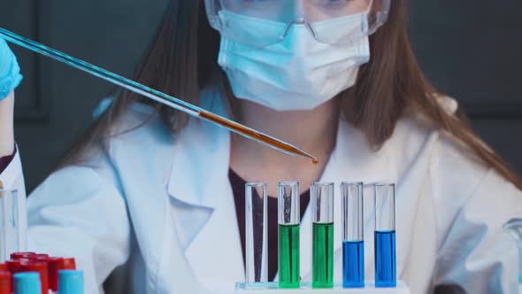 Female Scientist Dropping Samples of Color Liquid Into Test Tubes with Pipette Close Up