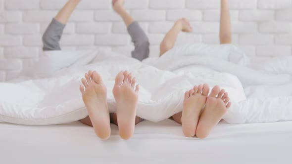 Close up feet of lesbian LGBTQ couple or friends in blanket moving hand