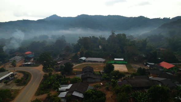 Aerial view a drone fly over a rural area with mountains in the background at sunrise.