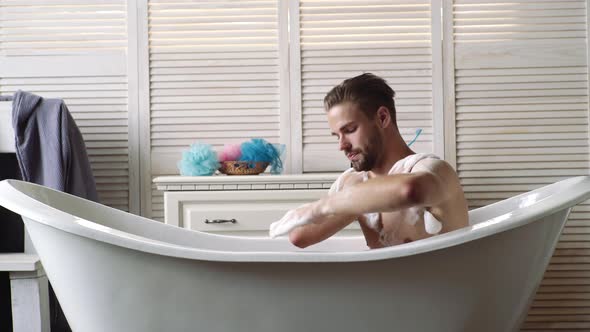 Confident Guy with Shaver in Bathroom. Bath Concept. Young Guy Bathing in the Bath in Bathtube. Gay