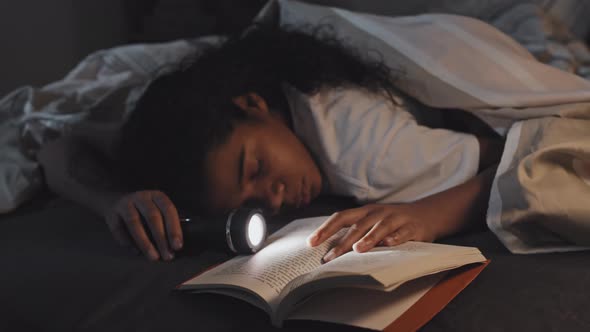 Girl Sleeping with Book and Flashlight