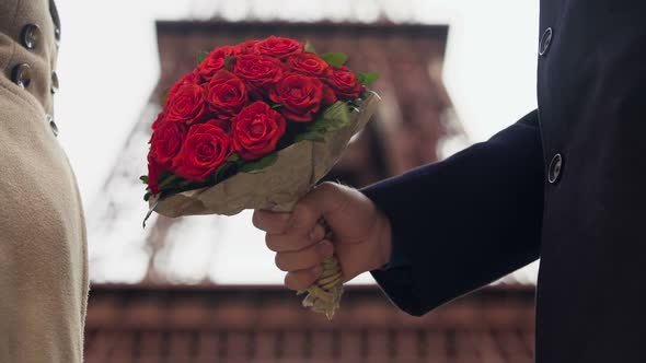 Attentive man giving beautiful bouquet of scarlet roses to his sweetheart