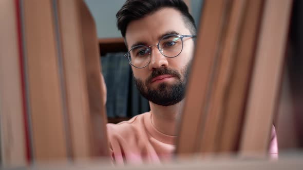 Confident Bearded Trendy Man Choosing Vintage Paper Book on Shelf at Public Home Library Closeup alt