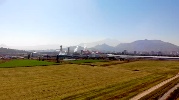 A sugar factory with smoke rising in the fields alt