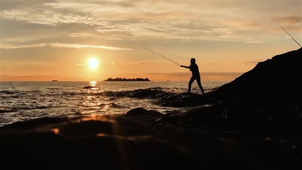 Silhouette of a Young Woman fishing at Sunset on the Beach.