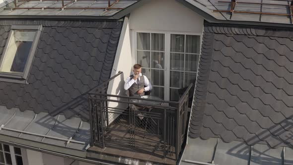 Man Groom Businessman Is Drinking Coffee From a White Cup on the Balcony at Home in Wedding Morning