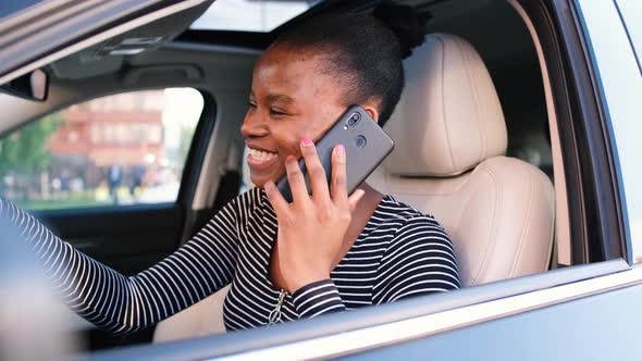Smiling African American Woman Talking on the Phone While Sitting in the Car