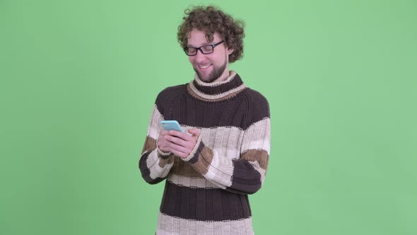 Happy Young Bearded Man Thinking While Using Phone