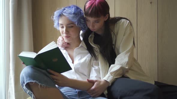Two Smiling Homosexual Young Woman Reading Book Together