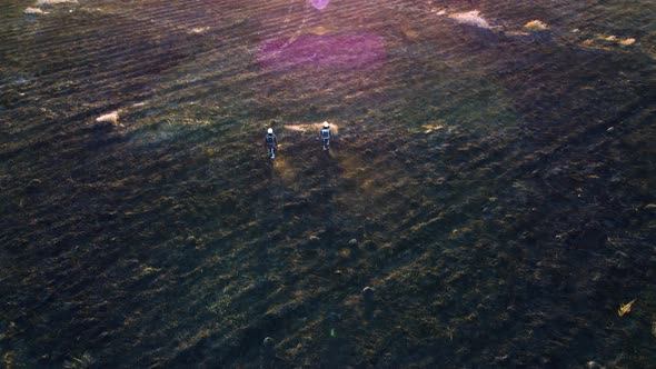 Two Firefighters Walk on Black Scorched Earth After Fire Dry Grass in a Field