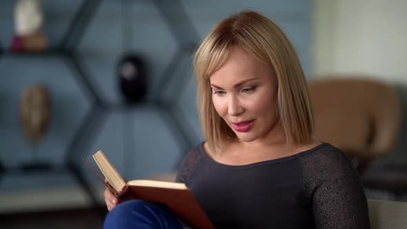 Close-up Portrait of a Pleasant Middle-aged Woman with Light Hair, She Is in the Office and Reading