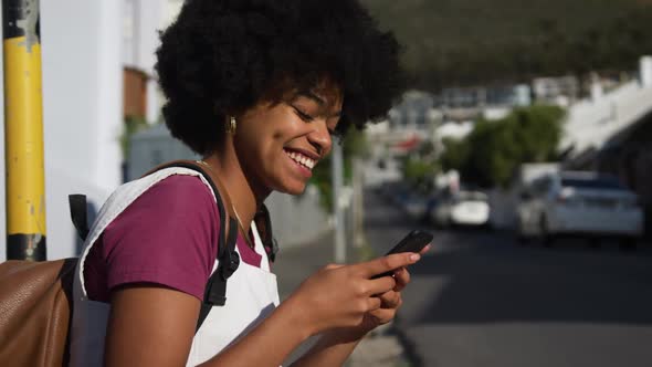 Mixed race woman on smartphone on sidewalk