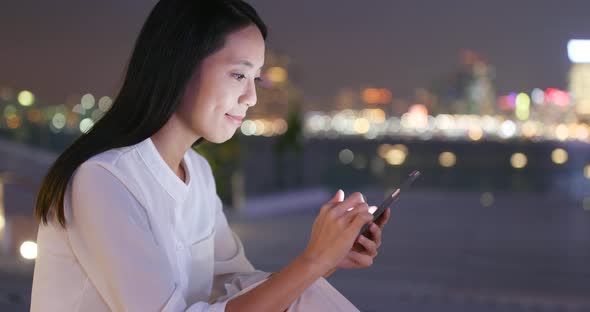 Woman using smart phone at night in the city