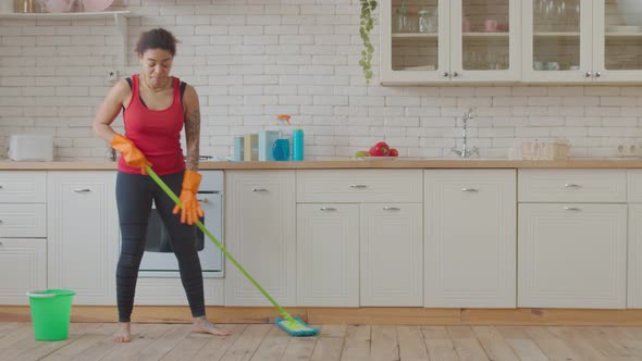 Positive Mixed Race Woman Mopping Kitchen Floor