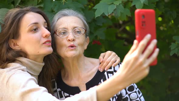 Adult Daughter and Senior Mum are Taking Selfportrait Picture Selfie on Red Smartphone Together