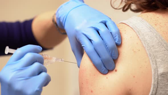 Nurse administers a vaccine shot to an adult female patient