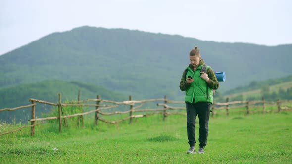 A Young Tourist with a Backpack Walks Along a Mountain Road