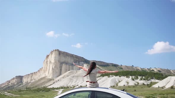 Happy Girl Sitting on Roof of Her Car, Relaxing and Enjoying Road Trip