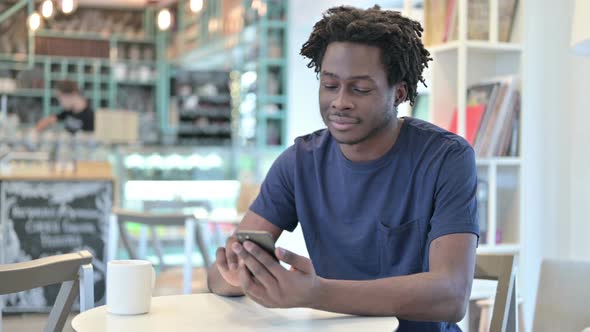 Smartphone Use By African Man in Cafe