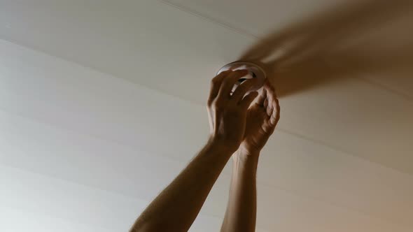 Men's Hands Twist the Light Bulb in the Ceiling Electric Energy-saving Lamp